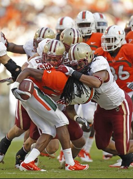 Miami's Travis Benjamin is stopped by a group of Boston College defenders on a kick off return in the second quarter of an NCAA college football game,...