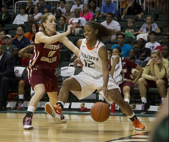 Miami's Krystal Saunders (12) drives around Boston College's Kerri Shields (10) during the first half of an NCAA women's college basketball game in...