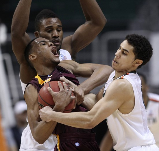 Miami players Erik Swoope, rear, and Shane Larkin  try to steal the ball away from Minnesota's Andre Hollins, center, during the second half of the...