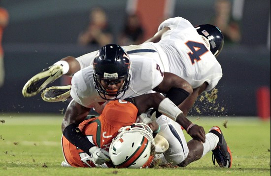 Virginia's Corey Mosley (7) brings down Miami quarterback Jacory Harris, bottom, as Rodney McLeod (4) jumps aside in the first half of an NCAA college...