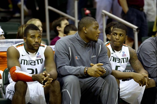 Miami basketball player Reggie Johnson, center, sits on the bench talking to teammates DeQuan Jones, right, and Erik Swoope during the first half of...