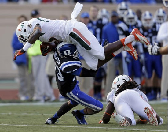 Miami's Herb Waters (6) jumps over Duke's Deondre Singleton, bottom left, during the first half of an NCAA college football game in Durham, N.C.,...