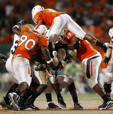 Georgia Tech quarterback Josh Nesbitt (9) is tackled by Miami's Stephen Wesley (90) and Marcus Forston (99) as Brandon Harris leaps onto the pile...