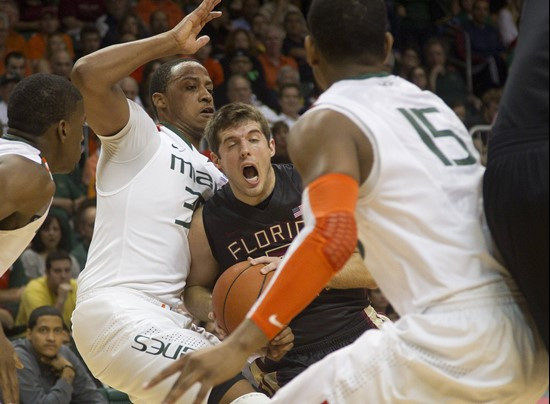 Florida State's Luke Loucks, center, reacts as Miami's Kenny Kadji (35) and Rion Brown (15) block him during the first half of an NCAA college...