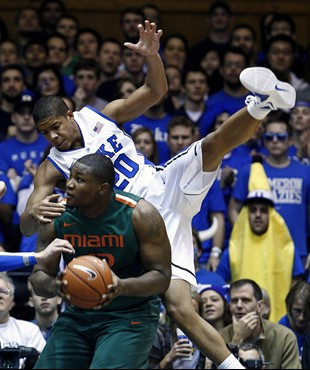 Duke's Andre Dawkins gets airborne while defending against Miami's Reggie Johnson during the first half of an NCAA college basketball game in Durham,...