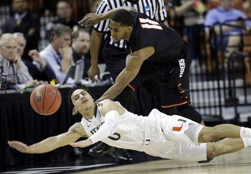Pacific's Lorenzo McCloud (11) and Miami's Shane Larkin (0) battle for a loose ball during the first half of a second-round game of the NCAA college...