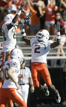 Miami running back Graig Cooper, right, celebrates with teammate Chris Zellner, top left, following his first quarter touchdown. (AP Photo/Phil Coale)